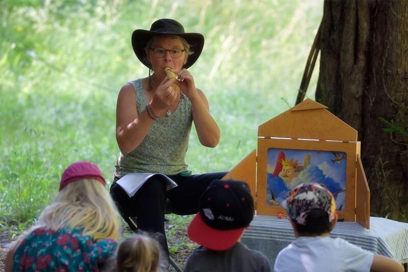 Lydie interprète un conte kamishibaï dans la nature devant des enfants